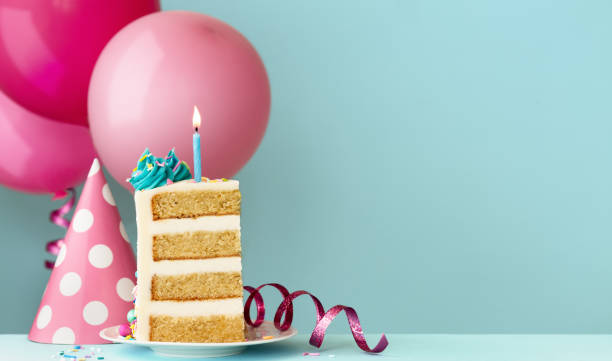 Slice of birthday cake with birthday candle and balloons stock photo
