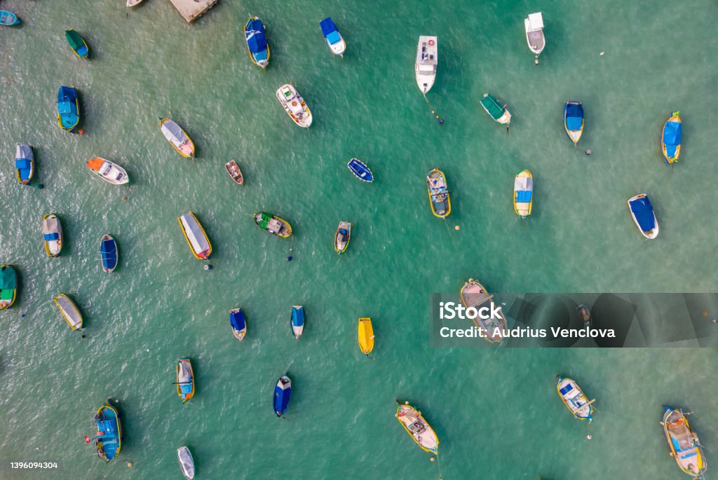 Aerial view of the colorful fisherman boats in Marsaxlokk, Malta Aerial panoramic view of colorful fisherman boats in Marsaxlokk - small, traditional fishing village in the South Eastern Region of Malta Fishing Boat Stock Photo