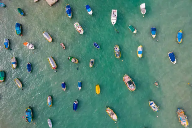 Aerial panoramic view of colorful fisherman boats in Marsaxlokk - small, traditional fishing village in the South Eastern Region of Malta