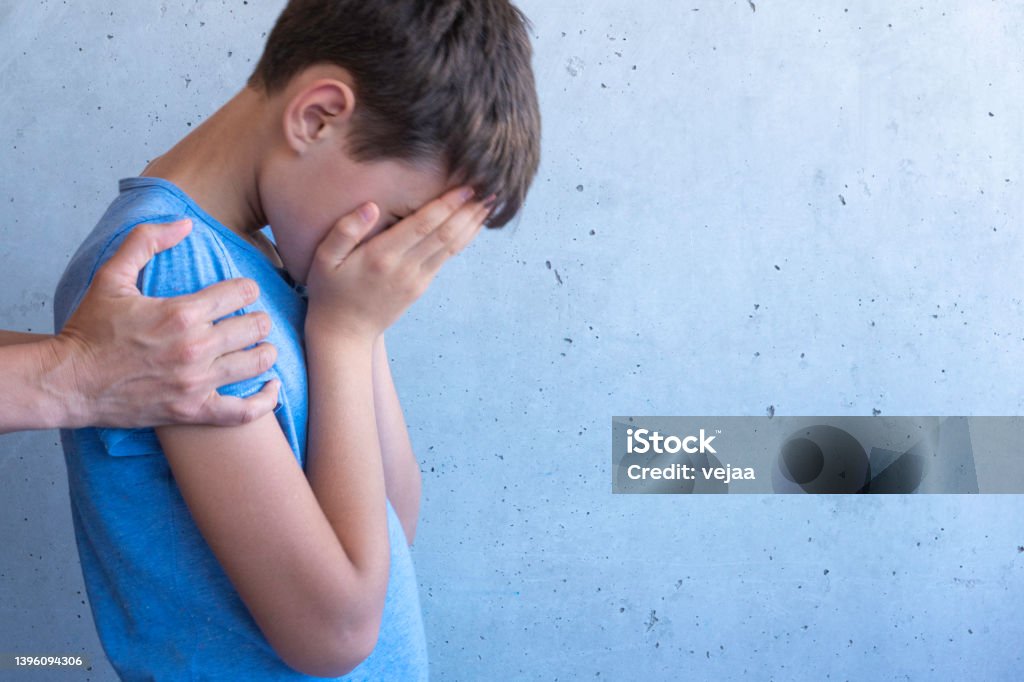 Mother hand hugging sad boy. Learning difficulties, family problems, bullying, depression, stress or frustration concept Mother hand hugging sad boy. Learning difficulties, family problems, bullying, depression, stress or frustration concept. Child Stock Photo