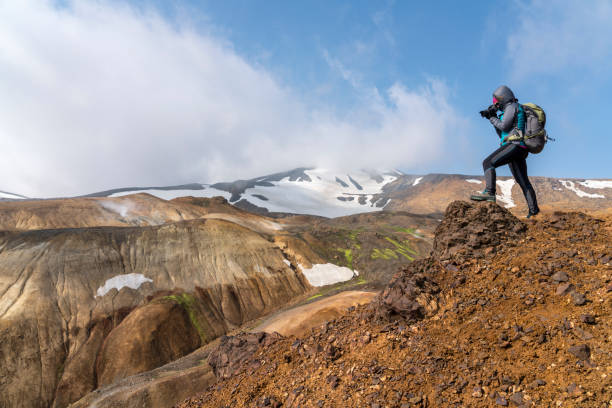 Women photographing the Hveradalir geothermal area Side view of women standing on top of the hill and photographing volcanic landscape, Hveradalir geothermal area on Kerlingarfjoll mountain range, Iceland kerlingarfjoll stock pictures, royalty-free photos & images