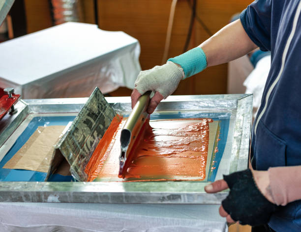 istock silkscreen printing. male hand with a squeegee. serigraphy production selective focus photo. printing images on clothes by silk screen method in a design studio 1396099795