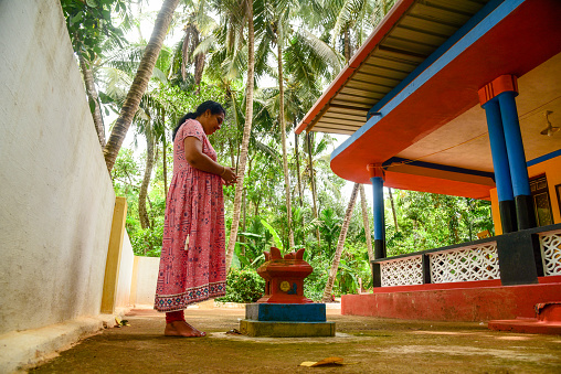 Indian women offering prayer to holy basil plant in front of home, kerala