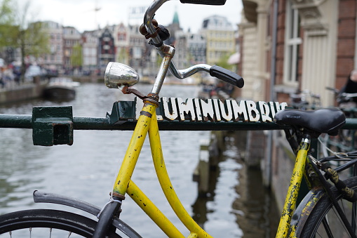 An old yellow bike is standing in a canal bridge in Amsterdam