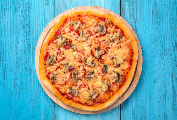 istock Pizza with tomatoes, mushrooms, cheese and tomato sauce on a blue background. 1396101854