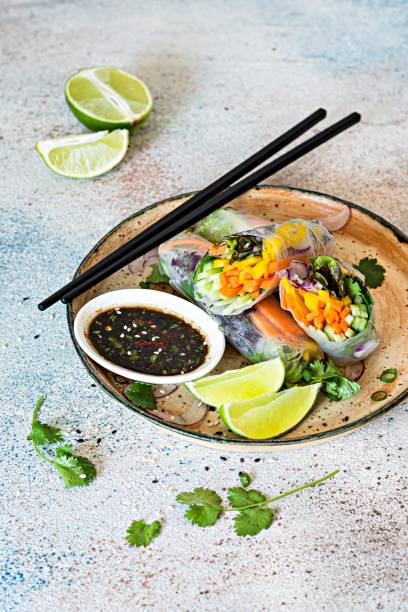 Fresh Asian appetizer Spring rolls (Nem) made from rice paper and raw vegetables and herbs with hot sauce on a light blue background. Vietnamese Food