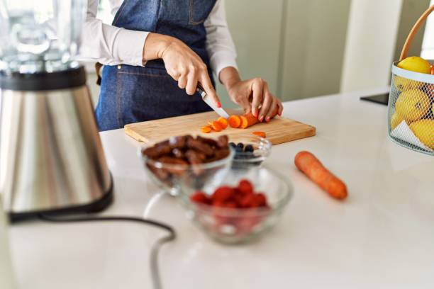 istock Young blonde woman cutting carrot at kitchen 1396102337