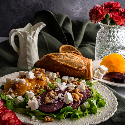 Superfood salad with sliced beets and oranges, feta cheese, and toasted walnuts on a bed of mixed greens. Served with a baguette