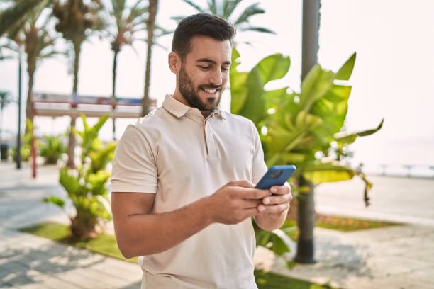 istock Young hispanic man smiling confident using smartphone at street 1396105105