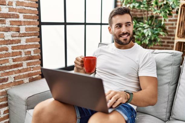 istock Young hispanic man using laptop and drinking coffee at home 1396105130