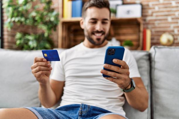 istock Young hispanic man smiling confident using smartphone and credit card at home 1396105149