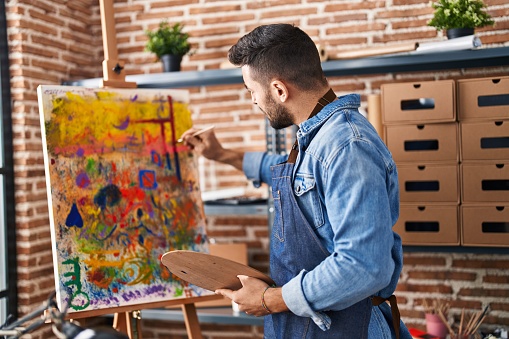 Young hispanic man smiling confident drawing at art studio