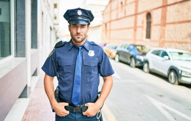 istock young handsome hispanic policeman wearing police uniform. Standing with serious expression at town street. 1396105356