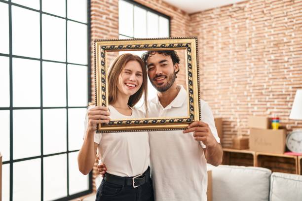 istock Young two people holding empty frame together winking looking at the camera with sexy expression, cheerful and happy face. 1396107604