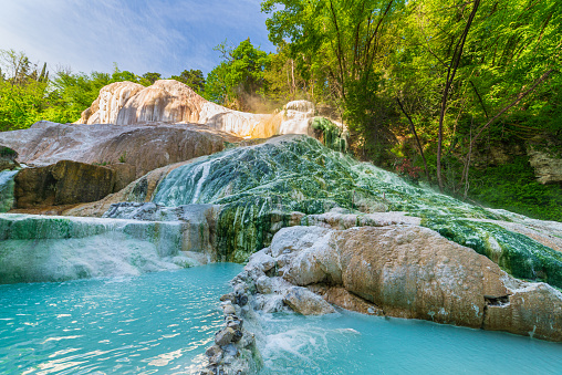 Geothermal pool and hot spring in Tuscany, Italy. Bagni San Filippo natural thermal waterfall in the morning with no people. The White Whale amidst forest.
