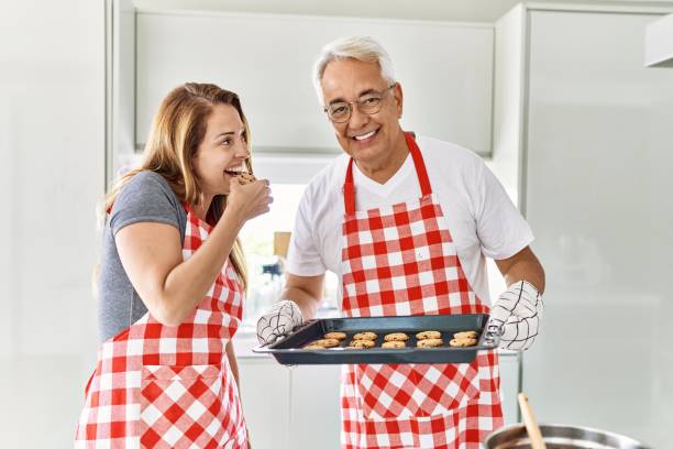 istock Middle age hispanic couple smiling happy baking cookies at the kitchen. 1396109200