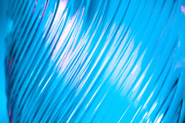 Abstract glass background. Texture of wavy glass illuminated with multi-colored light. Pink and blue stains. Close up. Flares on glass.