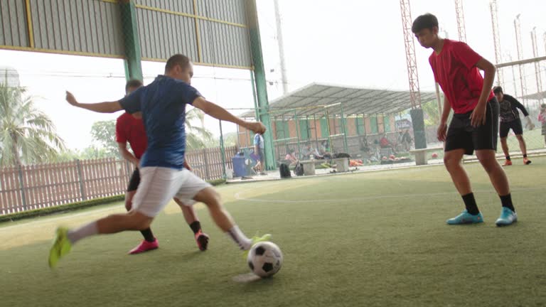 Mid adult male footballer dribbling around opponent