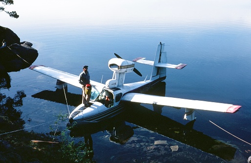 Young pilot candidate taking flight training looks at camera in front of retro airplane