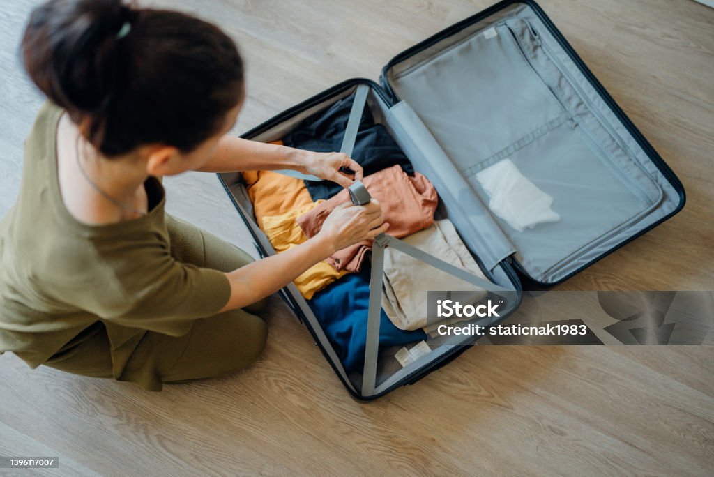 Woman packing suitcase at home for journey in vacation day. A young Woman Packing clothes into luggage at home, Thailand. Suitcase Stock Photo