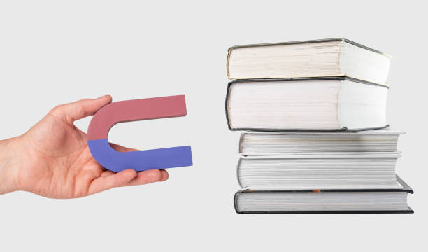 istock Woman hand holding magnet near books stack. Attracting, getting knowledge, wisdom from reading. Education and studying concept 1396117752