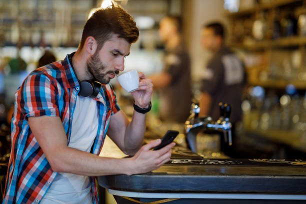 istock Handsome young caucasian man sitting at cafe using mobile phone and having coffee. 1396120722