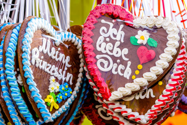 Gingerbread hearts hanging at a stand of the 2024  Oktoberfest in Munich, Germany. The hearts are decorated with colourful sugar and have sentences written on them.