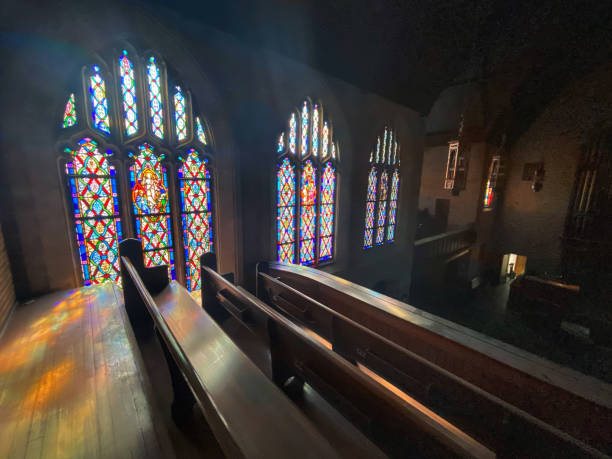 la lumière du soleil se déverse à travers les vitraux d’une église - pew photos et images de collection