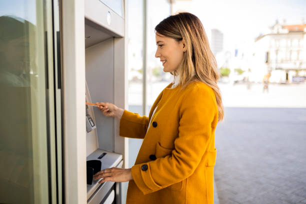 jeune femme sur le distributeur automatique de billets - guichet automatique de banque photos et images de collection