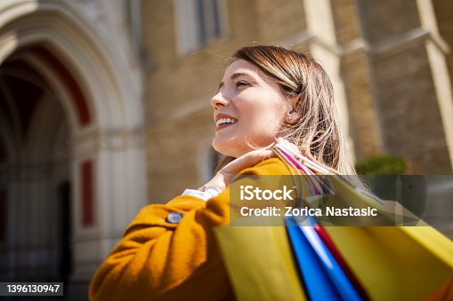 istock Smiling woman walking and carrying a shopping bag 1396130947