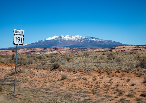 Utah highway 191 sign with desert landscape and snow covered mountain background