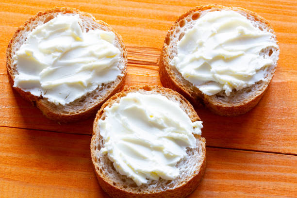 istock Sandwiches with cream cheese on the table. Sliced bread slices with soft cheese spread. Paste spread on a fresh French baguette. Homemade dessert for tea and coffee. Morning breakfast. Delicious snack 1396131179