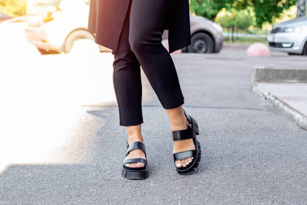 istock Female legs in black boots with stylish pedicure nails 1396132088