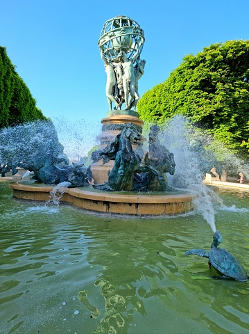 The Fontaine de l'Observatoire is a monumental fountain located in the Jardin Marco Polo, south of the Jardin du Luxembourg in the 6th arrondissement of Paris. The image shows the fountain which was realized in the time 1867-1874 during springtime.