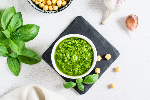 Homemade pesto sauce in a bowl and ingredients on the table. Healthy Italian cuisine. Top view. Close-up