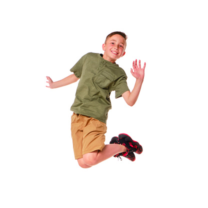 Happy boy jumping from stone  against green grass. Soft focus. Summer activities
