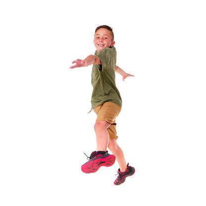 Adorable blond boy jumping and raises his hands up. Isolated on white background. Shooting in the studio