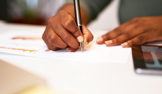 Close up of business woman's hands writing or making notes on document. Making notes on chart or graph