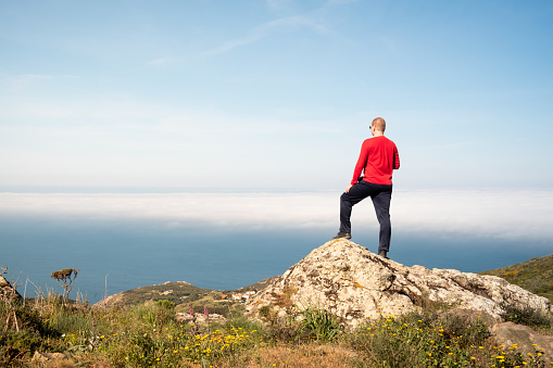 Man on top of the mountain looking at the sea above the clouds in Sintra