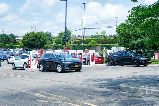 Several different Tesla BEV Model X, Model S and Model 3 cars (Battery Electric Vehicles - fully powered purely by electricity) are parked and plugged in while being recharged at a Tesla Supercharger station in this retail shopping mall parking lot in western NY State. Photo taken at Eastview Mall - 7979 Pittsford Victor Rd, Victor, NY 14564, on July 20, 2019. This mall is located about 14 miles southeast of the city of Rochester, NY.