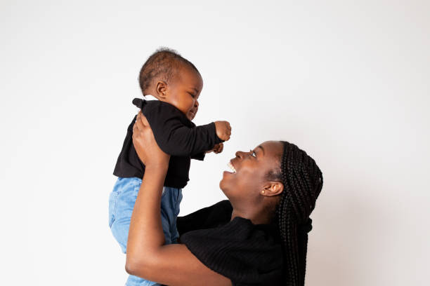 Beautiful Black woman holding her baby daughter portrait, on neutral background