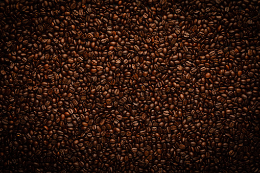 Roasted coffee abstract background. Texture in dark brown tones with vignette and edges darkening