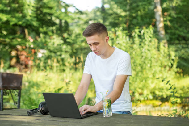 osoba inspirowana naturą. korzystaj z internetu, laptopa i słuchawek do pracy zdalnej i nauki. pyszny orzeźwiający koktajl z miętą i cytryną - office park audio zdjęcia i obrazy z banku zdjęć