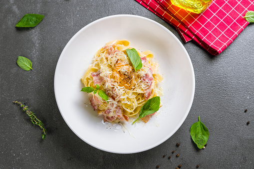 Fettuccine Carbonara with parmesan and egg on a white plate top view on grey table