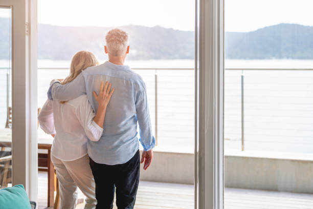 istock Mature couple looking at the view in their waterfront home. 1396146996