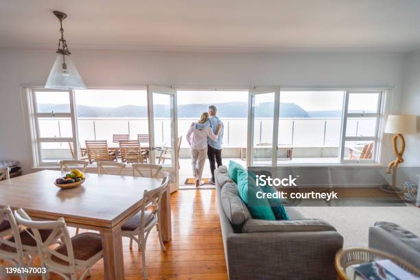 Mature Couple Looking At The View In Their Waterfront Home Stock Photo - Download Image Now
