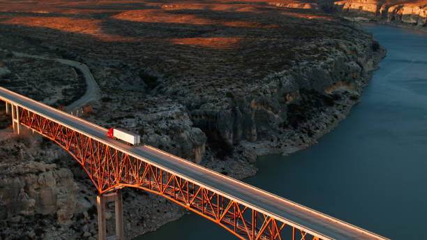 drone ad alto angolo di scatto del camion che attraversa il ponte sul fiume pecos - trasporto merci via terra foto e immagini stock