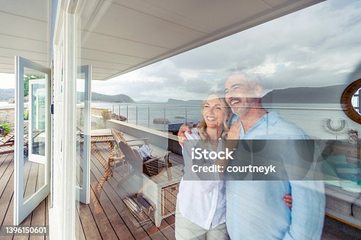 istock Mature couple looking at the view in their waterfront home. 1396150601