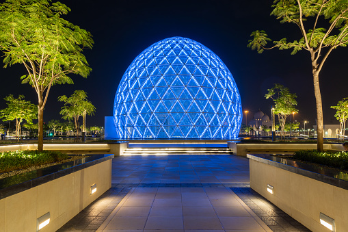 Blue illuminated sphere dome located next to Sheikh Zayed Grand Mosque in Abu Dhabi UAE, shot at night. The largest mosque in the country