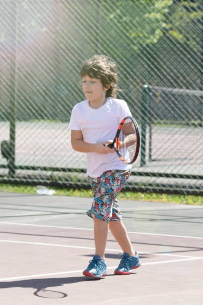 istock Happy boy playing tennis outdoors with a friend. 1396155458